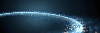 Glowing particles forming curved light trail against dark background, sparkling blue energy wave with bokeh effect and motion blur for technology designs.