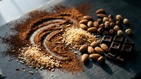 Cocoa powder swirl with coffee beans, chocolate pieces and nuts on dark surface for baking and confectionery preparation.