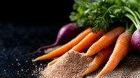 Fresh organic carrots, red onions and parsley with scattered brown spices powder on dark rustic wooden background, raw healthy ingredients for cooking.