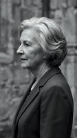 Elegant senior woman in profile wearing business suit against stone wall background. Black and white portrait showcasing wisdom and professional confidence.