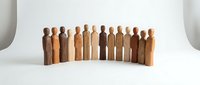 Wooden peg dolls in various skin tones arranged in a curved line, representing diversity, inclusion, and community on white background.