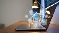 Smart home automation technology concept with digital house icons floating above laptop computer screen in modern office workspace for IoT applications.