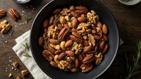 Mixed nuts roasted in cast iron skillet with pecans walnuts almonds on rustic wooden table for healthy snacking cooking baking recipe ingredients.
