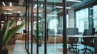 Modern office interior with glass walls and partitions showing empty meeting room with ergonomic chairs, green plants, and fluorescent lighting creating professional atmosphere.