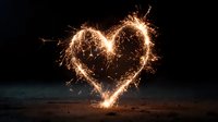 Glowing heart shape created with sparklers against dark night background, symbolizing love, celebration, and romantic moments.