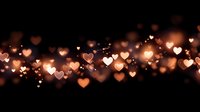Romantic golden heart bokeh lights floating on dark background creating warm atmospheric glow for Valentine's Day, wedding, anniversary celebrations.