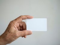 Mature man with medium skin tone holding blank white business card or ticket in hand against neutral background for branding and marketing purposes.