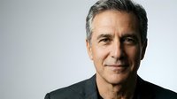 Mature man with gray hair and facial stubble wearing dark clothing against neutral background, suitable for corporate, business, and professional portraits.