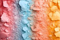 Crushed colorful eyeshadow powder texture in pink, blue and orange shades forming rainbow gradient pattern, close up view of cosmetic pigments.