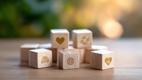 Wooden dice with romantic love symbols and hearts engraved on sides, arranged on blurred natural background with soft bokeh lighting effect.