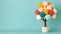 Decorative cotton ball tree in pastel and bright colors arranged in white basket against turquoise background, creating whimsical home decor composition.