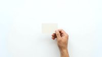 Male hand holding blank cream colored card against white background for business messaging and branding purposes.