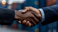 Professional business handshake between African American and Caucasian male executives in suits, symbolizing partnership and agreement, with blurred background.
