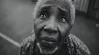 Elderly African American man with gray beard looking upward with hopeful expression in black and white portrait photography for emotional storytelling projects.
