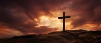 Silhouette of wooden cross on rocky hill against dramatic sunset sky with golden clouds for spiritual and religious themes.