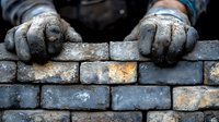Construction worker hands in protective gloves laying brick wall with mortar. Professional masonry work building residential or commercial structure.