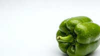 Fresh green bell pepper isolated on white background for healthy cooking and nutrition concepts.