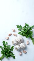 Fresh garlic bulbs and cloves with green parsley herbs arranged on white background for culinary cooking and healthy food preparation.