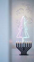 Modern holiday celebration with neon Christmas tree lights, menorah candles and floating glass ornaments creating festive interfaith winter atmosphere.