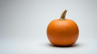 Fresh orange pumpkin with natural stem isolated on white background for autumn harvest decoration and seasonal design projects.