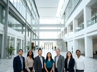 Diverse group of business professionals standing together in modern corporate atrium with glass architecture, natural lighting, and contemporary office building interior for corporate team portraits.