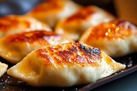 Pan-fried dumplings with golden-brown crispy bottom and tender dough, glistening with oil on dark plate, extreme close up showing texture and caramelization.