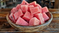 Fresh cut watermelon cubes in wooden bowl on rustic table, summer fruit snack ready to eat, healthy natural food for refreshing treats and recipes.