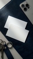 Blank business card mockup on navy blue leather with smartphone and keys, flat lay top view for branding and identity design.