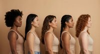 Five diverse women in profile wearing neutral tank tops showcasing different ethnicities and natural hair textures for beauty diversity campaigns.