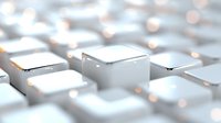 Macro view of white computer keyboard keys with soft focus and bokeh lighting effects, creating modern minimalist technology background pattern.
