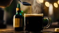 Steaming hot coffee poured into glass mug with green handle against dark background with bokeh lights, morning beverage photography.