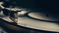 Vintage turntable with stylus needle on vinyl record in warm lighting. Classic analog music equipment for audio production and entertainment industry.