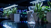 Modern office interior with hourglass timer and green plants under LED lighting creating productive workspace atmosphere for business productivity concepts.