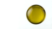 Overhead view of golden olive oil in a glass bowl isolated on white background, suitable for food and culinary design projects.