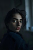 Young Middle Eastern woman with dark hair wearing cozy sweater looking over shoulder in moody indoor lighting for lifestyle and portrait photography.