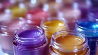 Colorful cosmetic cream jars with vibrant purple, yellow, blue and pink formulations for skincare and beauty product manufacturing.