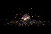 Glowing particles and sparkles creating magical light effect against black background, floating dust bokeh for festive design and holiday atmosphere.