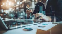 Businessman analyzing financial data and stock market charts on laptop with holographic display overlay, reviewing investment performance and trading analytics in modern office environment.