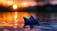 Paper boat floating on calm water surface at sunset with golden sun reflection creating dreamy atmosphere. Artistic nature photography with bokeh effect.