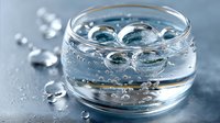 Clear water with air bubbles in round glass bowl on blue background, creating fresh, pure, hydrating effect for spa, wellness, or cosmetic concept.