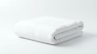 White fluffy bath towel folded neatly on neutral background, suitable for spa, hotel, hospitality, and wellness marketing materials.