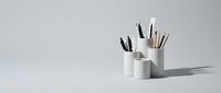 Minimalist white desk organizer with pencils and pens on a light gray background, perfect for office and workspace design concepts.