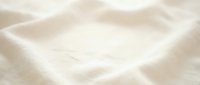 Soft cream colored fabric with gentle folds and wrinkles creating elegant textile background for luxury fashion and interior design projects.