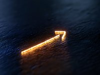 Glowing golden arrow pointing upward on dark textured surface creates dramatic lighting effect, symbolizing growth, success and forward momentum in business concepts.