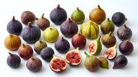 Fresh figs in various stages of ripeness arranged on white background, showcasing purple, green, and golden varieties with some cut open to display interior seeds and flesh.