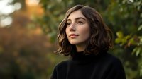 Young Mediterranean woman with wavy brown bob haircut wearing black turtleneck sweater looking away thoughtfully against blurred autumn nature background.