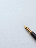 Golden fountain pen nib on white textured paper background with copy space, minimalist composition for writing, creativity and communication concepts.