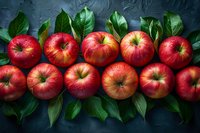 Fresh red apples arranged in rows with green leaves on dark background, water drops add natural freshness, top view composition for food photography.