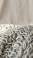 Cozy gray knitted wool blanket with chunky cable pattern texture closeup for home decor and comfort concepts.