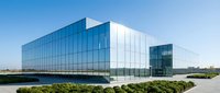 Modern glass and steel corporate office building with reflective facade situated beside water feature and manicured landscaping, suitable for business, architecture, and commercial real estate projects.